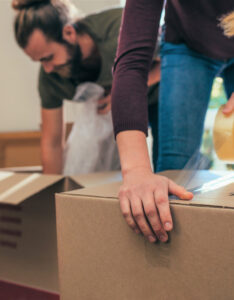 Close up of two people packing cardboard boxes with tape