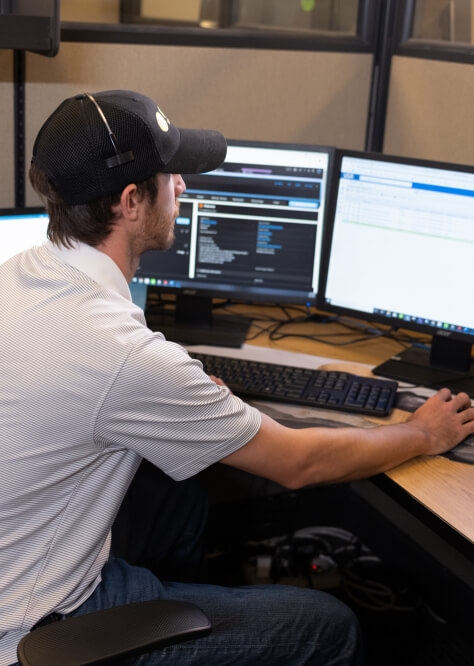 Man sitting a desk, working on two desktop computer screens