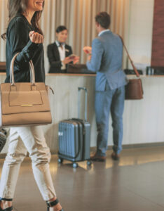Hotel lobby, showing various people checking in and walking around with luggage