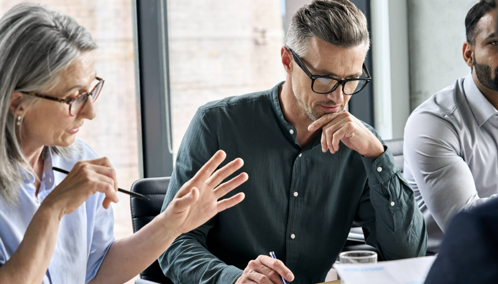 Two people engaged in conversation while in an office meeting room.