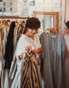 Woman shopping at a clothing boutique. She is holding a shirt.