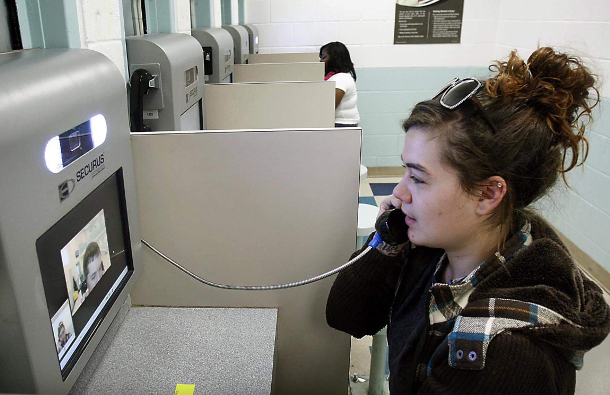 woman using securus kiosk to talk to inmate