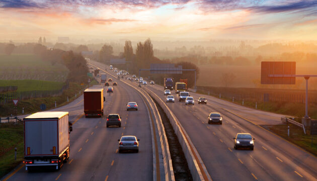 Traffic on highway with cars at sunset and fog on the horizon