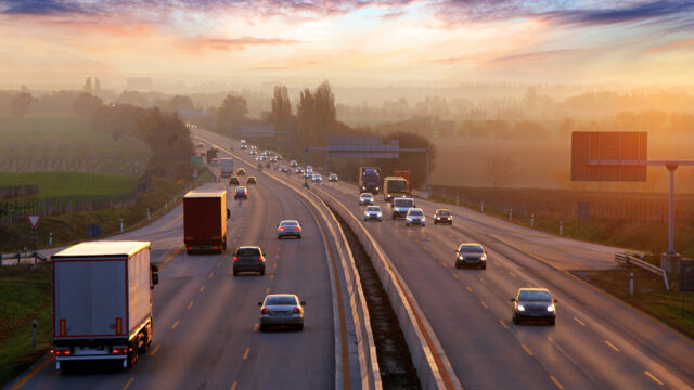 Traffic on highway with cars at sunset and fog on the horizon