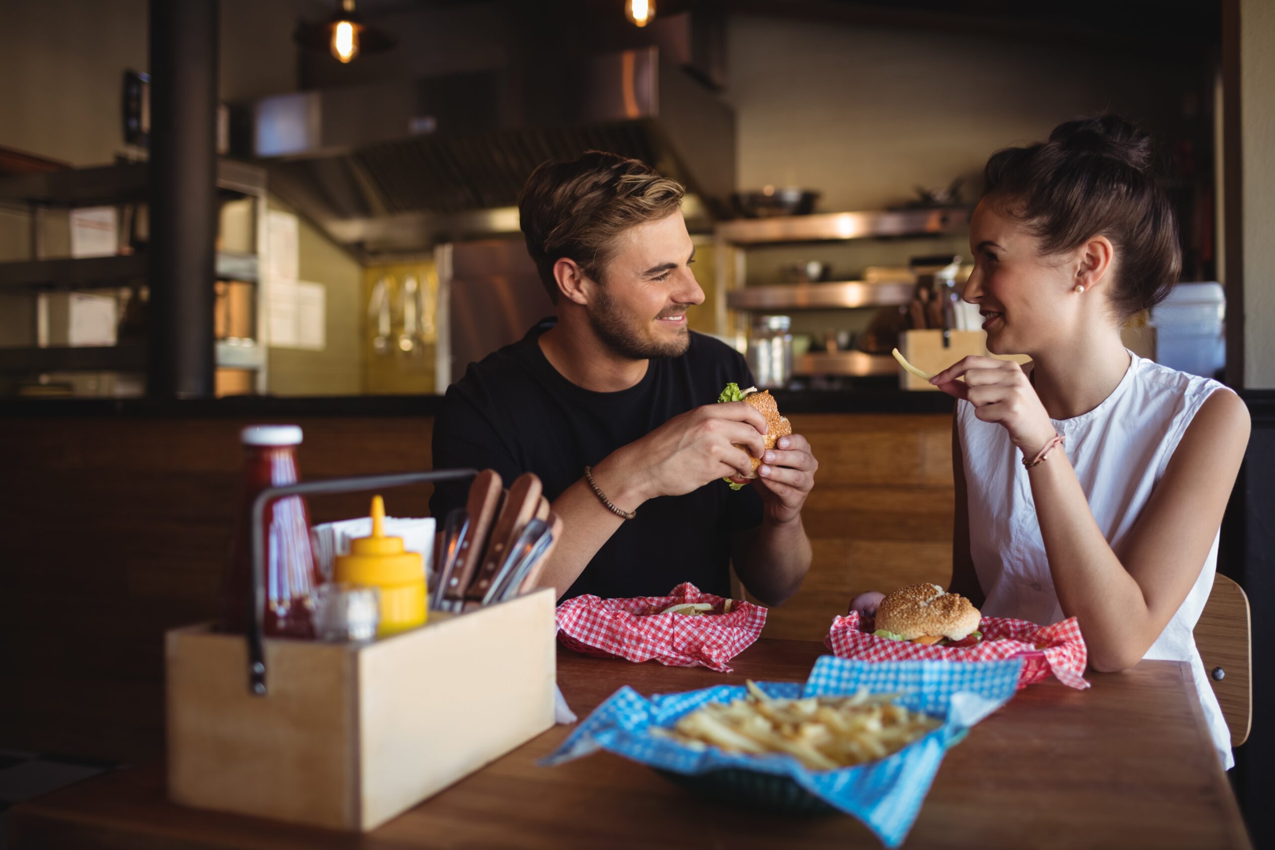 couple eating burgers in a restaurant and talking