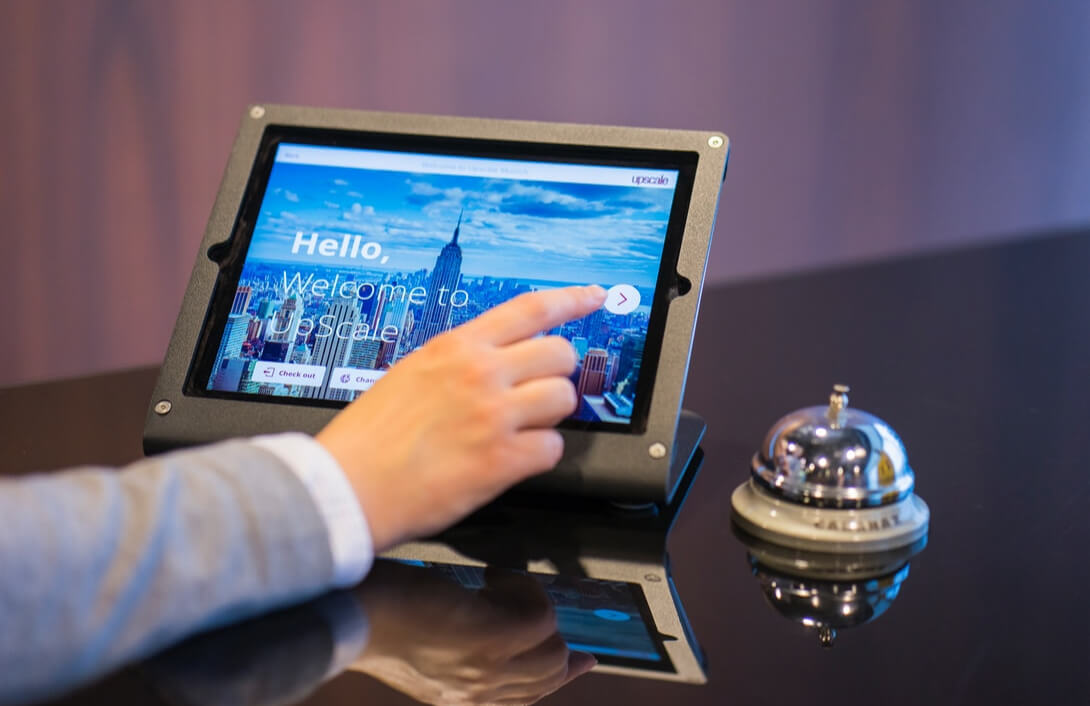 person's hand touching a kiosk at a hotel desk