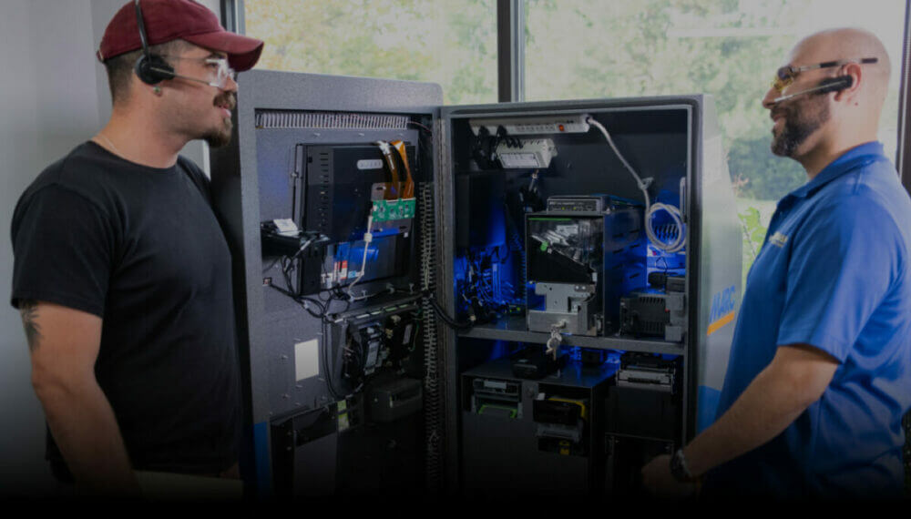 two technicians looking at the inside of a kiosk