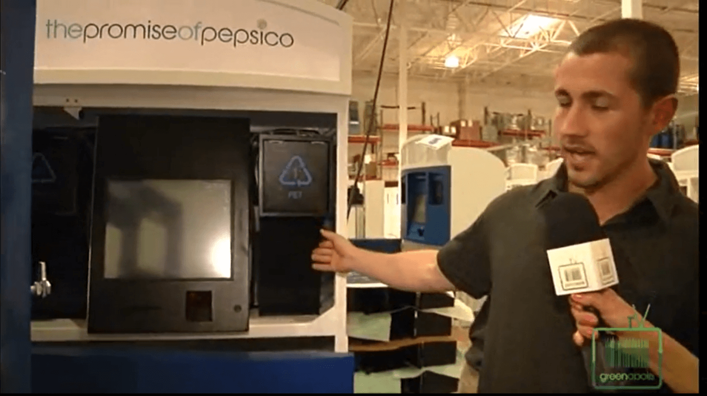Man being speaking into a microphone while showcasing pesico kiosk