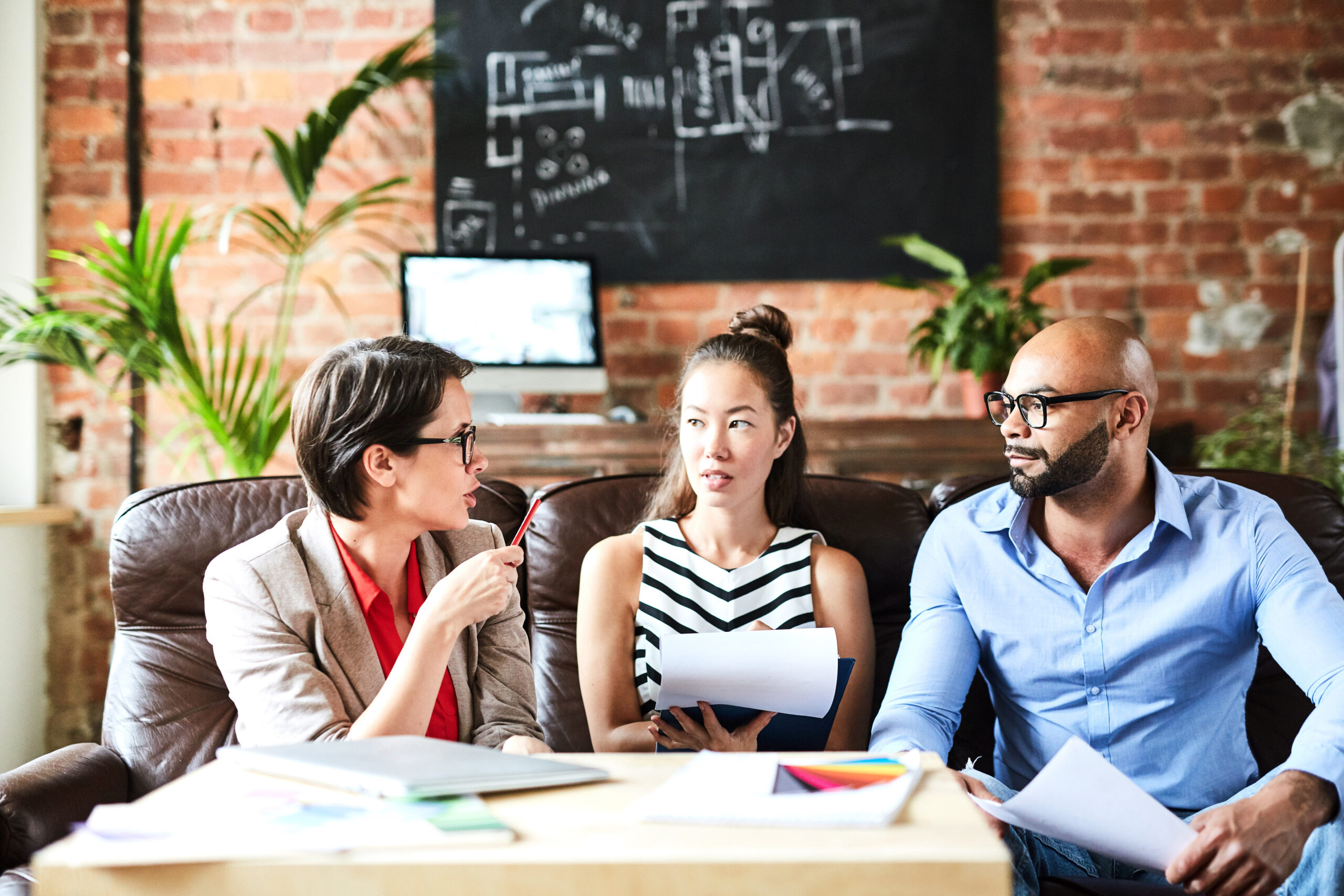 three people discussing a project sitting on a couch