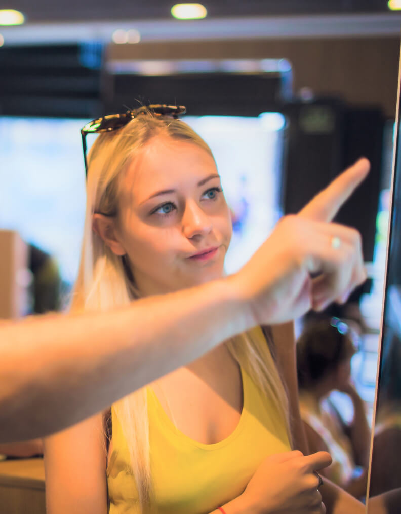 Young woman watching someone interact with the kiosk screen
