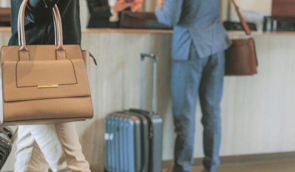 Hotel lobby, showing a man checking in with a receptionist and a woman walking with luggage