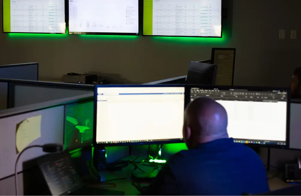 A man works in front of five computer monitors