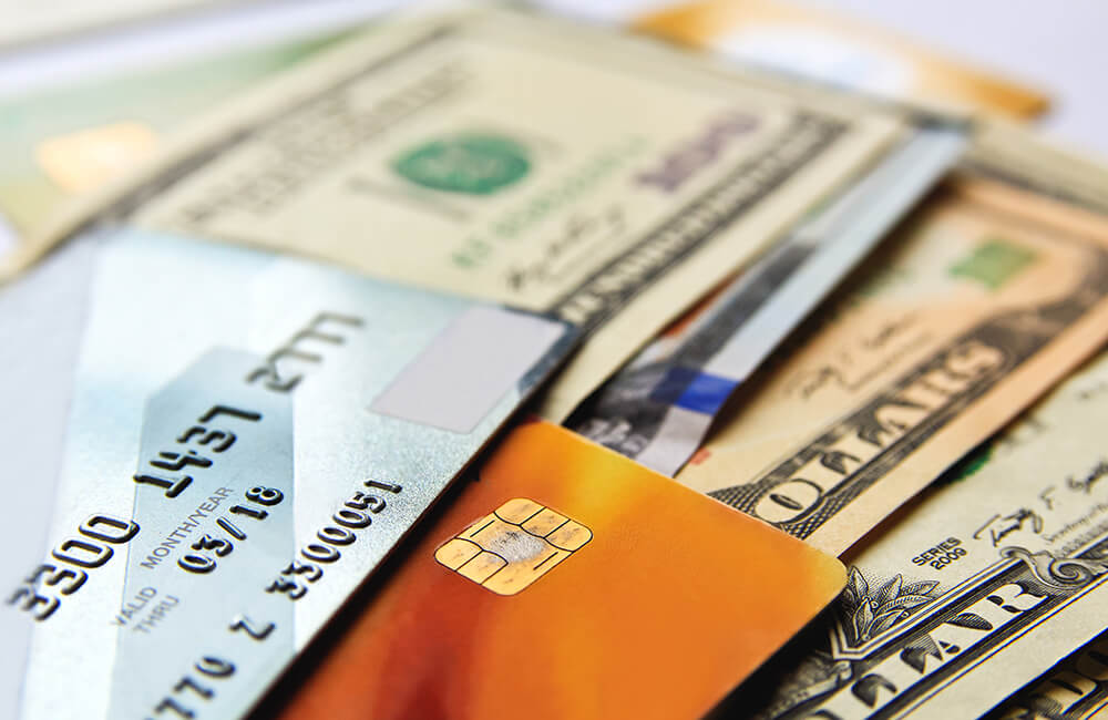 Stack of credit cards and American dollars cash, close-up view.