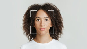 Biometric facial recognition of calm young African American female, on gray background.